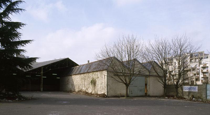 Vue des sheds, ancien atelier de distillation des goudrons des Comptoirs Français E. Mignot, depuis la cour du site industriel.