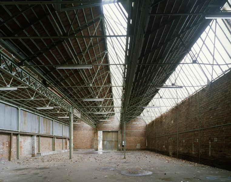 Vue intérieure des sheds à pans de fer et remplissage briques (ancien atelier de distillation des goudrons des Comptoirs Français E. Mignot).