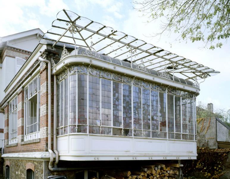 Détail de l'oriel protégé par une marquise construit en métal et verre du jardin d'hiver.
