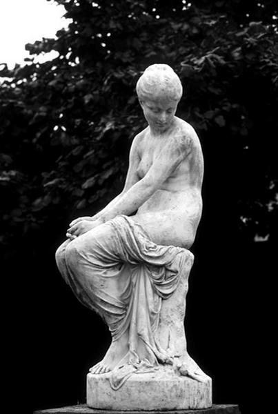Vue d'ensemble de la sculpture représentant une nymphe, assise, se penchant sur deux hirondelles. Le groupe est placé dans la cour du Centre technique du bâtiment.