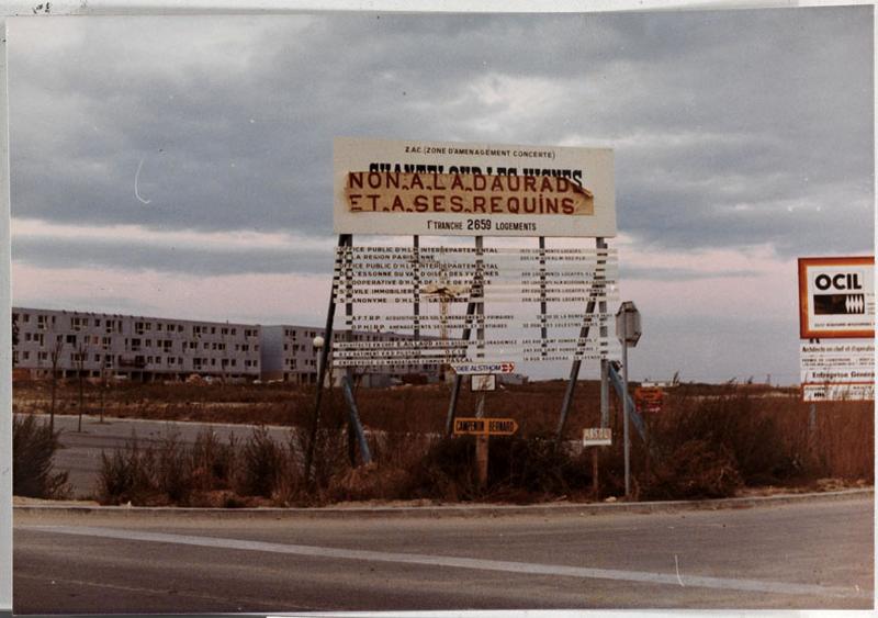 Panneau de chantier de la ZAC de Chanteloup, précisant ' première tranche 2659 logements '. Une banderole portant le slogan ' non à la daurade et à ses requins ' le recouvre en partie.
