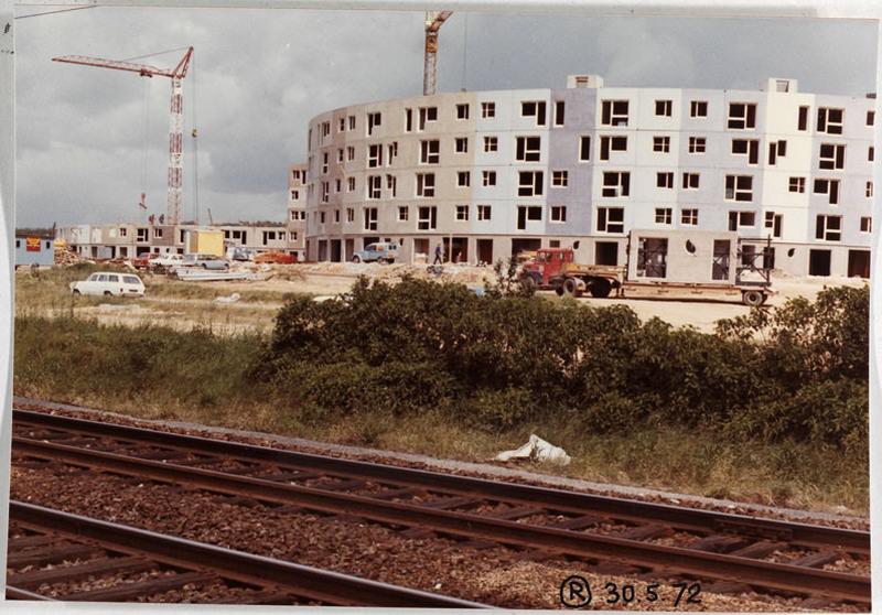 Vue du chantier prise depuis les voies de chemin de fer. A droite, un camion transporte un panneau préfabriqué de RDC.