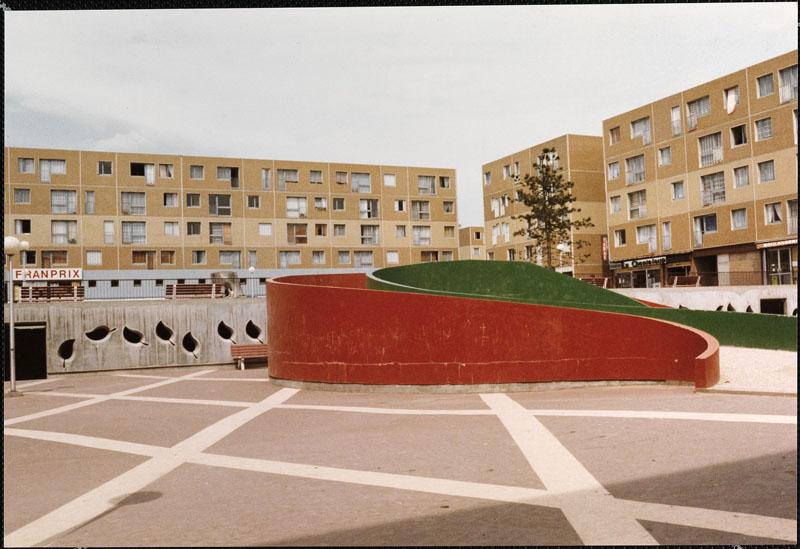Vue de la partie basse de la place du Pied. Au sol, un tracé blanc constitue un effet de dallage. Une rampe conduit à la partie haute de la place (qui abrite en dessous des parkings). Le bâtiment plot au centre est aujourd'hui détruit.