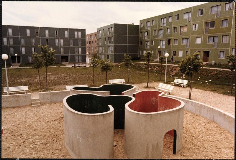 Vue de la cour Verte. Au premier plan, l'espace de jeu (aujourd'hui détruit) : une étendue de sable et un élément en béton peint se déployant comme un ruban et formant des espaces où se cacher.