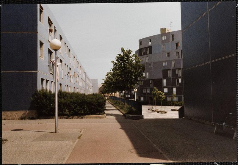Vue de l'entrée dans la place du Béguinage. A gauche des jardins privatifs associés aux logements en rez-de-chaussée.