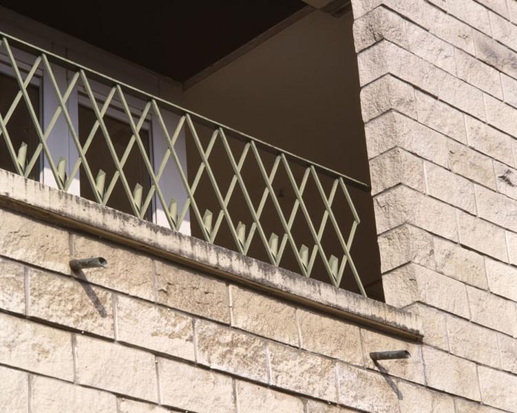Détail d'une loggia et de son garde corps métallique. On distingue bien la maçonnerie en parpaing de béton.
