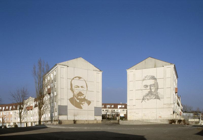 Vue actuelle de la place de la Coquille. A gauche correspondant au pignon du bâtiment ouest de la place du Trident, le portait de Gérard de Nerval ; à droite, le pignon du bâtiment est de la place du Trident, le portrait de Stéphane Mallarmé.