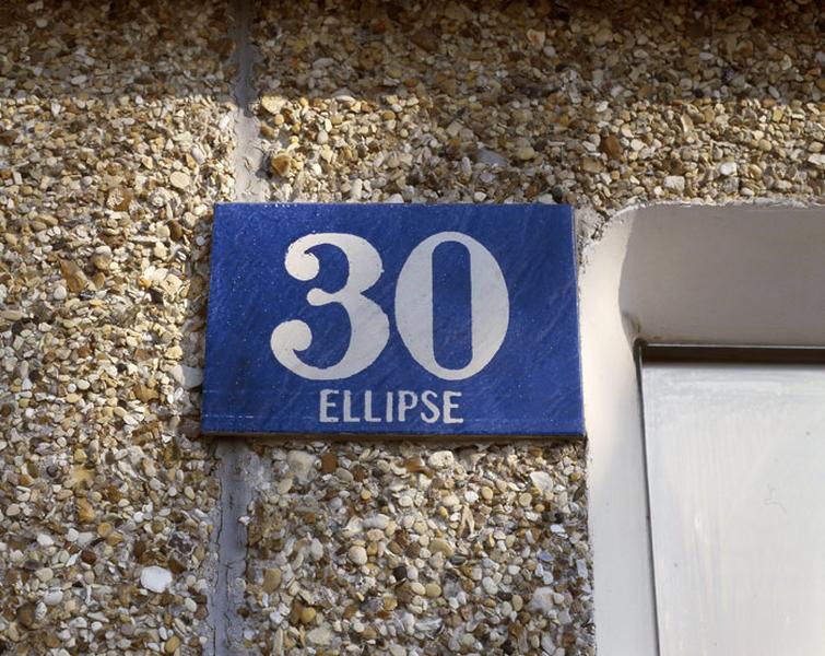 Détail d'une plaque de numéro de rue en céramique vernissée indiquant le 30 du bâtiment de l'Ellipse.