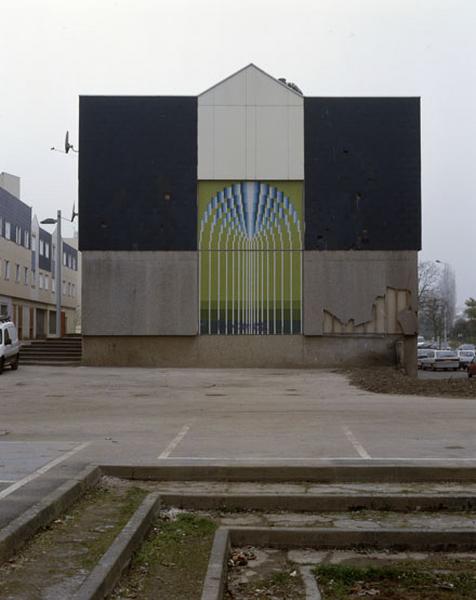 Détail actuel d'un mur pignon de la place des Arcades orné d'un décor de fontaine stylisée.