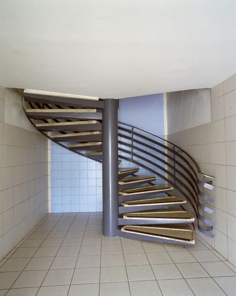 Détail d'un escalier en vis en métal et dont les marches sont constituées d'une plaque de granito, desservant les étages (dans un des bâtiments de la place de l'Echauguette).