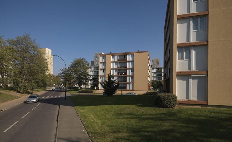 La rue Frédéric-Joliot-Curie, bordée d'un côté par des bâtiments 'pavés', en direction de l'avenue de la Concorde.