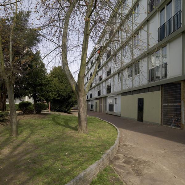 Chemin piétonnier bordé d'une pelouse desservant un immeuble linéaire donnannt sur la rue Jules-Vallès.
