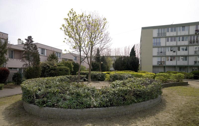 Massif végétal entouré d'un muret composé de pavés près de la place Ampère.