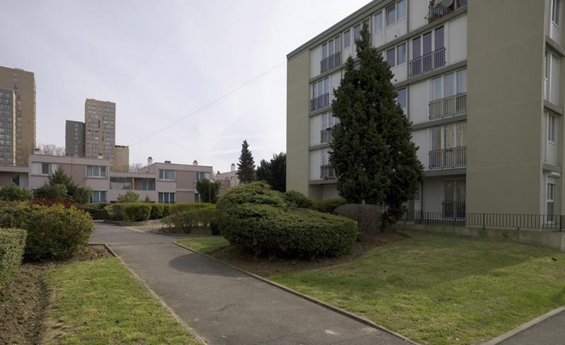Immeuble 'pavé' de la place Ampère ; à l'arrière plan, immeuble de logements individuels en bande et tours.