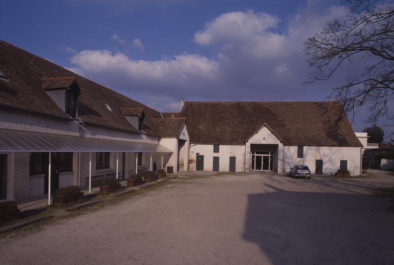 Les bâtiments agricoles disposés en équerre sur deux côtés de la cour.