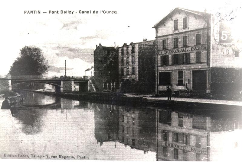 Carte postale du Canal de l'Ourcq, à la hauteur du Pont Delizy, sur laquelle on distingue l'entrepôt industriel de la manufacture de grès Duborjal.