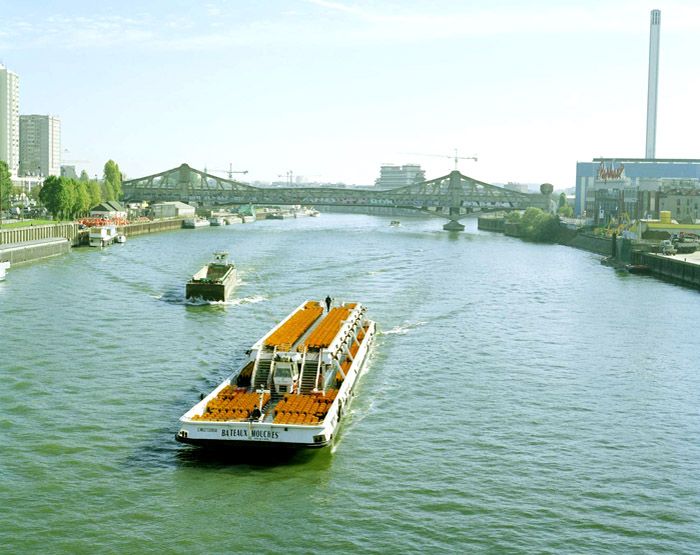 Ivry-sur-Seine, Charenton-le-Pont. Passerelle industrielle d'Ivry-Charenton. La passerelle dans le lointain, au premier plan un bateau mouche.