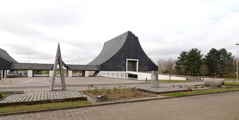 Au centre, le portique d'entrée vu depuis l'intérieur du cimetière, à droite, le bâtiment des cérémonies. Au premier plan, des éléments de la sculpture monumentale de Székely.