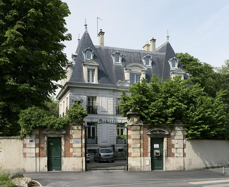 Vue d'ensemble de l'entrée de la propriété : portail encadré de deux portes piétonnes. Les piliers sont ornés par deux vases Médicis en fonte.