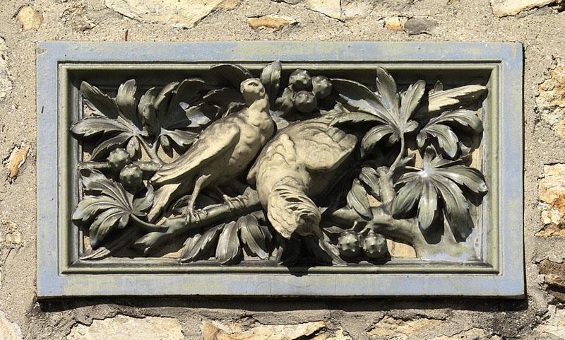 Détail de l'un des décors de céramique en bas-relief. Motifs animal et végétal : couple de perdrix dans des branches de châtaigner.