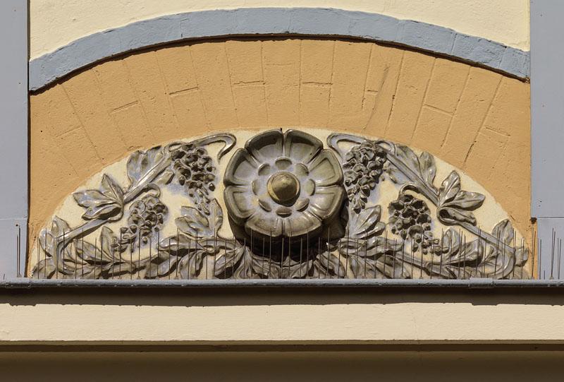 Détail de l'un des décors de céramique en bas relief : rosace entourée de branches fleuries.