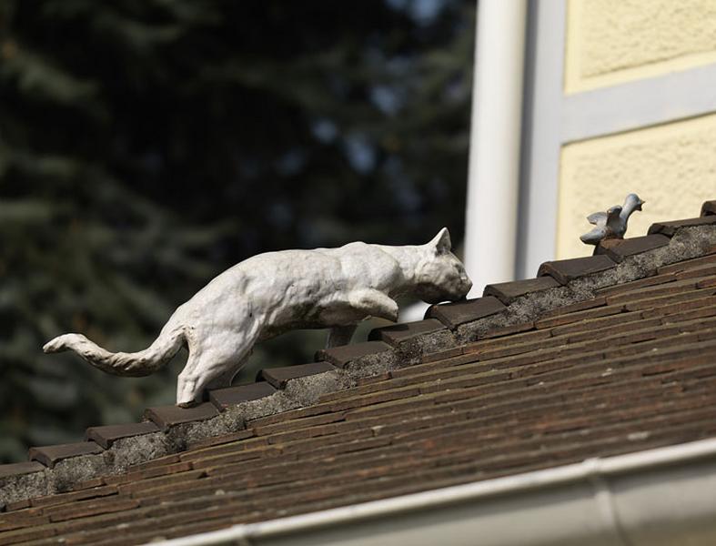 Détail de l'un des ornements (arêtier) de faîtage du toit de la maison (toit en appentis de l'entrée) en céramique vernissée, avec représentation animale : chat guettant l'oiseau.