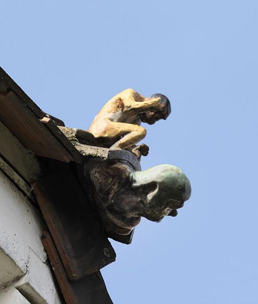Détail de l'un des ornements de faîtage (antéfixe) du toit de la maison (façade sur rue) en céramique vernissée. Homme assis et visage.