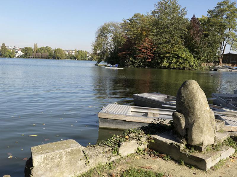 Vue du lac avec au premier plan les vestiges d'une sculpture, probablement un lion, qui devait orner l'entrée de l'un des nombreux embarcadères qui bordaient les rives du lac. Aujourd'hui, cette sculpture est située au bout de la promenade de la presqu'île aux fleurs.