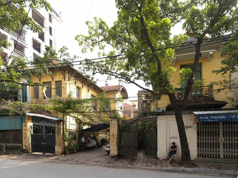 Lotissement, 59 rue Tran Quoc Toan. Vue d'ensemble d'une maison jumelée, faisant partie du lotissement. La structure en longueur s'associe aux larges ouvertures et à des jardinets. La grille de la porte est ornée du caractère signifiant 'longue vie'. Une dizaine de maisons s'ordonne autour d'un passage étroit. Elles présentent des plans identiques avec deux styles de décor, l'un plus moderne, avec des colonnes en béton, l'autre plus traditionnel, avec un jeu de corbeaux en bois. A l'intérieur, une grande pièce divisée par une arcature donne sur un escalier. Les détails sont soignés. Tout laisse à penser qu'il s'agit de la réalisation d'un architecte destinée à des habitants vietnamiens. C'est peut-être même l'un des rares exemples d'habitat à bon marché construit par la municipalité.