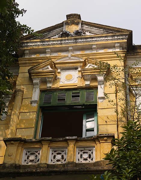 Détail de la façade d'une école : baie avec balcon surmontée d'un fronton.