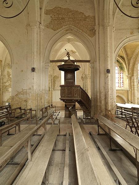 Vue intérieure : la 3e travée de la nef, avec ses bancs et la chaire à prêcher.