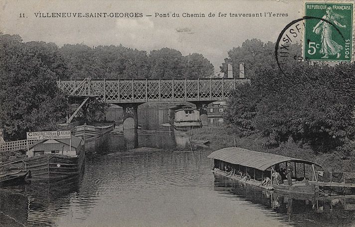 Villeneuve-Saint-Georges. Pont ferroviaire sur l'Yerres. Vue du pont métallique, avec au premier plan, un bateau-lavoir et des lavandières au travail. Carte postale. ( Musée de la batellerie, Conflans-Sainte-Honorine)