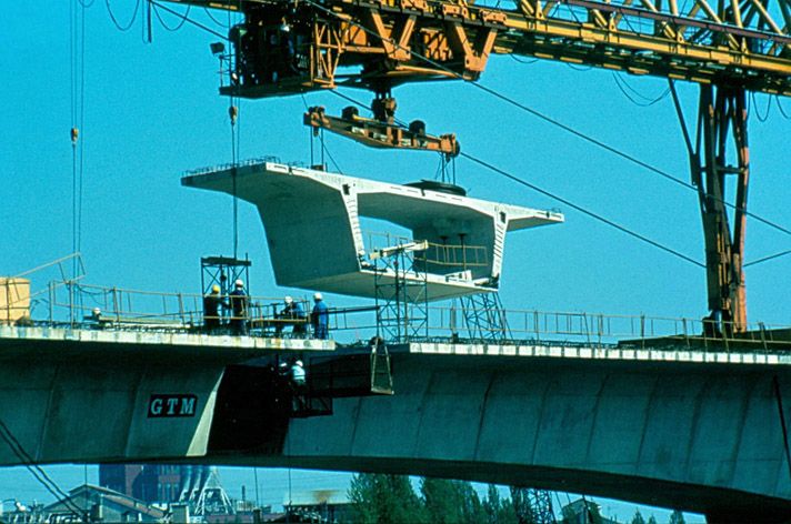 Choisy-le-Roi, Alfortville, Vitry-sur-Seine. Pont de Choisy de l'A86. Vue du chantier. Mise en place d'un voussoir encore suspendu à la grue. Photographie. (Ecole nationale des ponts et chaussées. 2 S 039)