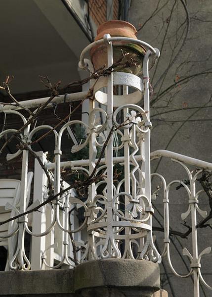 Détail de l'escalier extérieur en ferronnerie conduisant du jardin au rez-de-chaussée surélevé, probablement dessiné par Emile Robert, ferronnier d'art. Détail de l'angle formant un piédestal circulaire pour accueillir un pot de fleur.