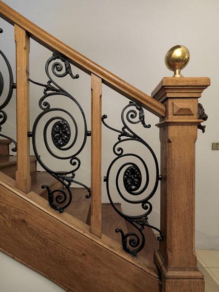 Détail de la rampe d'escalier en bois et ferronnerie.