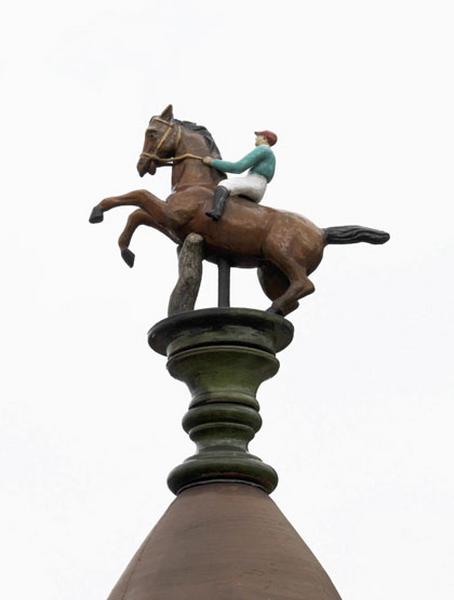 Vue de l'épi de faîtage couronnant le pavillon néo-normand : jockey sur son cheval, profil gauche.