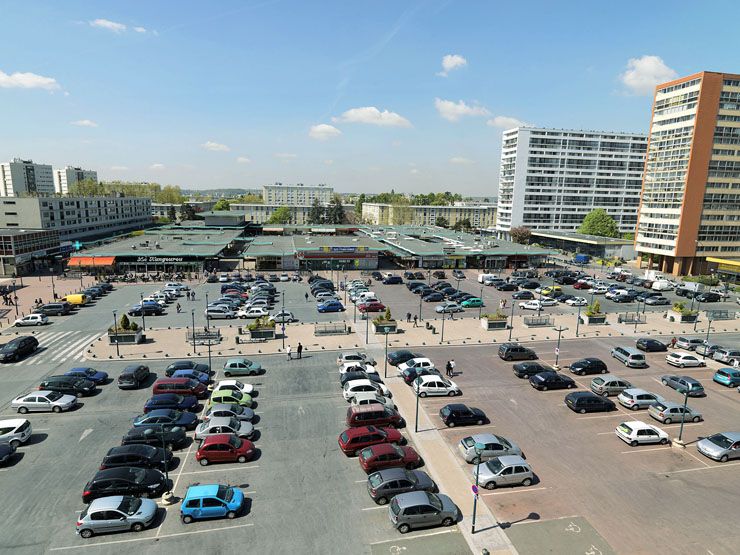 Vue semi-aérienne du parking et du centre commercial.