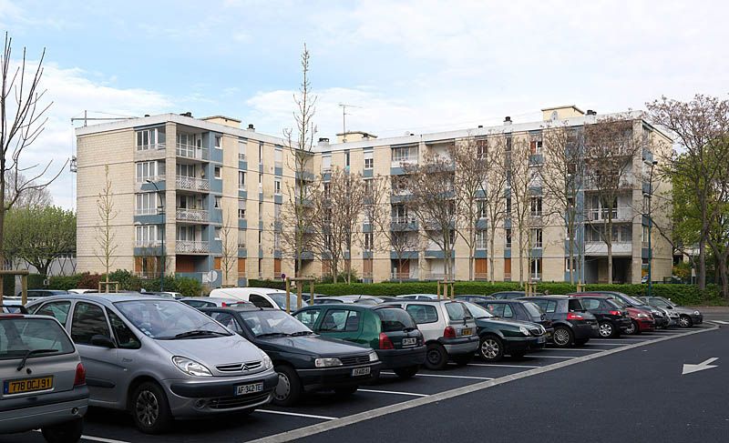 Bâtiment 2 délimité par des haies taillées qui dissimulent un square aménagé au pied de l'immeuble. L'avenue du Noyer-Lambert sépare ce bâtiment en L du parking prévu pour cet ensemble de logements.