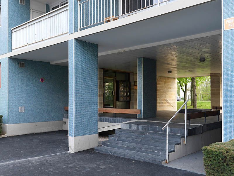 Vue d'un des deux sous-porches du bâtiment 3 resté dans son état d'origine. la multiplicité des matériaux : pierre brute, ardoise, mosaïque de grès cérame, bois verni, donne le parti pris décoratif de l'architecte.
