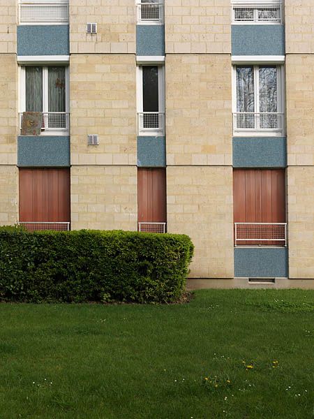 Détail de la partie inférieure d'une façade. Fenêtres étroites verticales et les allèges accentuent la verticalité renforcée par l'usage des matériaux altéernés : pierre de Saint-Maximin et mosaïque de grès cérame bleu.