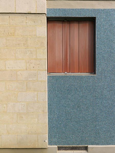 Détail de deux panneaux de façade : parpaings de pierre de Saint-Maximin et mosaïque de grès cérame bleu marqués par une discontinuité horizontale.