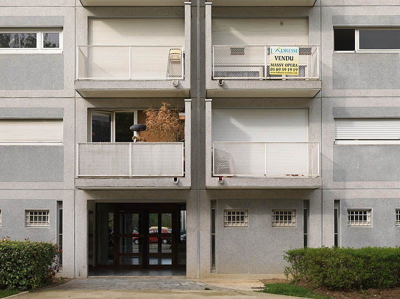 Entrée de l'immeuble R+9 situé square Yves du Manoir. La façade symétrique combine trois types de modules: module avec balcon pour les séjours, module avec fenêtre en bande pour les chambres, module avec jour horizontal et fenêtre à barreaudage. L'espace vide entre les deux module de balcons marquent la ligne de symétrie.
