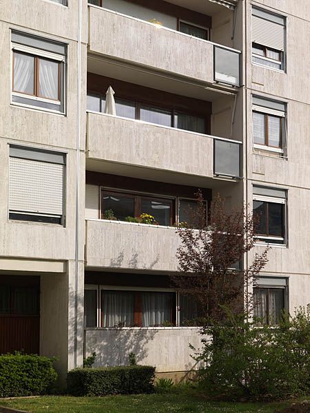 Détail d'une travée de façade composée de panneaux préfabriqués : l'utilisation du travertin romain pour les garde-corps des balcons et le parement créent une unité dans la façade.