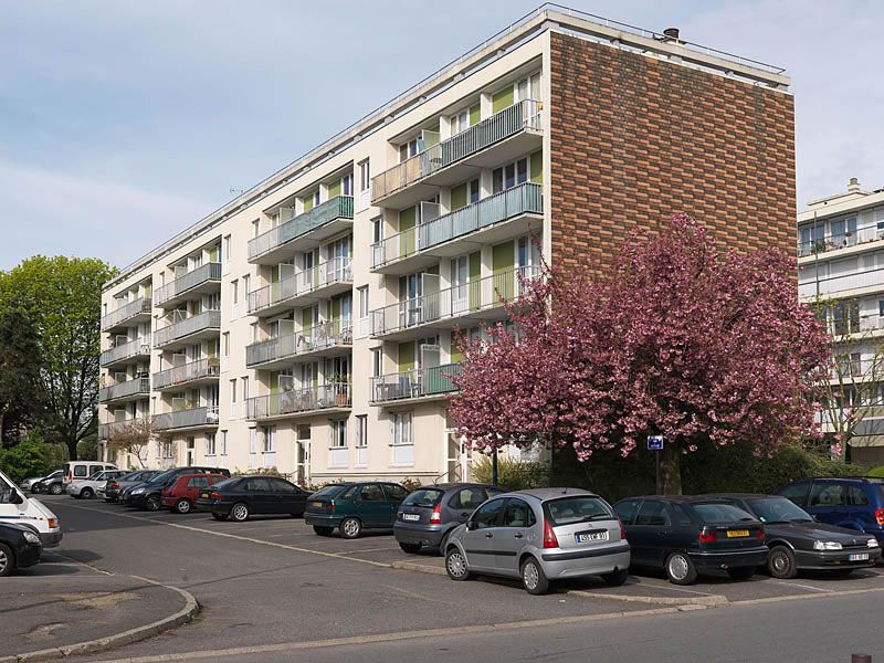Façade et pignon d'une des deux barres R+4 situées sud-ouest du grand ensemble, excentrées du reste de l'opération. Le pignon est recouvert de bois de différentes teintes.