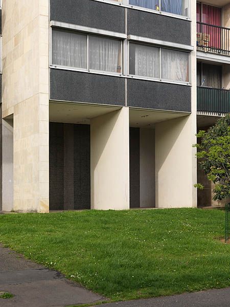 Rez-de-chaussée d'une barre R+13 située avenue Nationale. Les rez-de-chaussée occupent deux niveaux et sont coupés par des murs rideaux formant une galerie couverte autour de l'immeuble.
