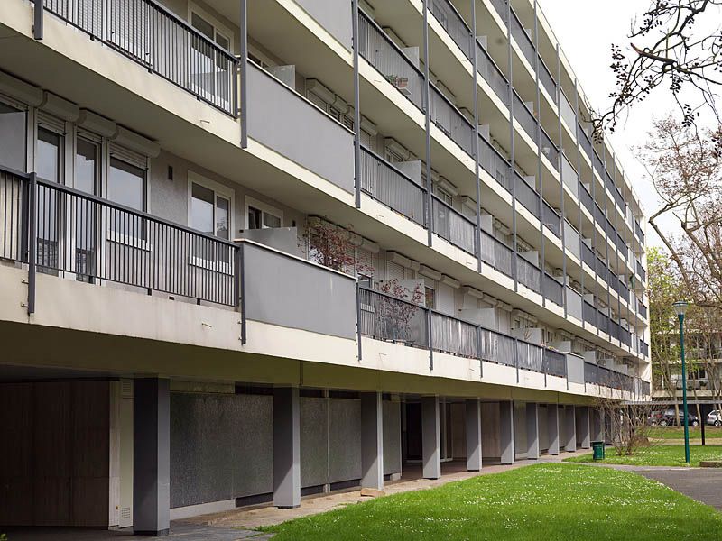 La façade côté jardin. Les rez-de-chaussée sont traversant, les piliers permettant la circulation des piétons. Les façades sont animés de balcons filants avec garde-corps métalliques.