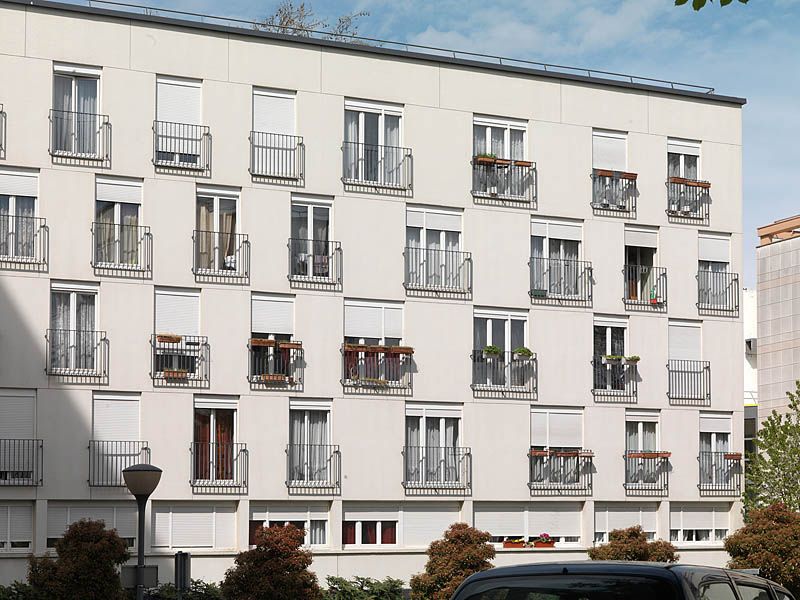 Vue de la façade côté rue avec deux types de fenêtres ayant toutes des garde-corps métalliques. La réhabilitation des façades a été réalisée en 2004, financée en Palulos.