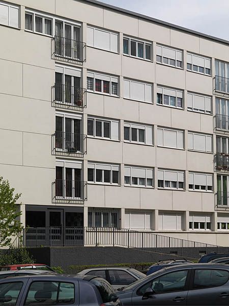 Façade principale orientée côté parking et rampes d'accès. L'accès au hall d'entrée surélevé a été réhabilité en 2004 grâce à un financement Palulos.