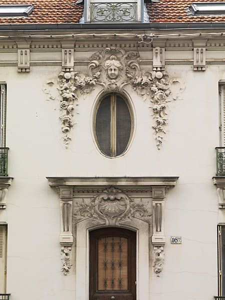 Ablon-sur-Seine, maison, 16-ter rue du Bac. Détail de l'élévation antérieure: la travée centrale. La porte est surmontée d'un entablement composé d'une corniche avec cimaise et denticules, porté par deux consoles qui encadrent une cartouche d'inspiration rocaille. L'oeil-de-boeuf du second niveau est couronné par un cartouche chantourné ornée d'un mascaron, encadré par des guirlandes de fleurs enrubannées.