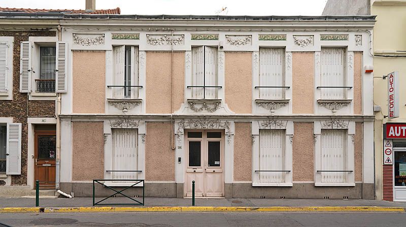 Ablon-sur-Seine, maison, 16 rue du Bac. Elévation antérieure portant un décor sculpté en bas-relief de motifs floraux sur le dessus-de-porte et les dessus-de-fenêtre au rez-de-chaussée, au premier, les dessus-de-fenêtres sont décorés de céramiques polychromes et les encadrements ornés de bas-reliefs de motifs floraux Une corniche sépare les deux niveaux et une seconde couronne l'ensemble.